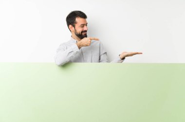 Sakallı genç yakışıklı bir adam elinde kocaman boş bir levha tutuyordu. Avucunda hayali bir şey vardı. Bir ilan vermek için.