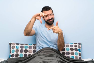 Yatakta yüzüne odaklanan bir adam. Çerçeve sembolü