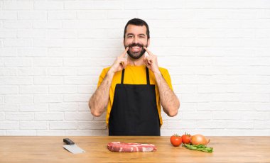 Şef bir mutfakta mutlu ve hoş bir ifadeyle gülümsüyor.
