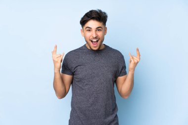 Arap yakışıklı adam izole edilmiş arka planda boynuz hareketi yapıyor.