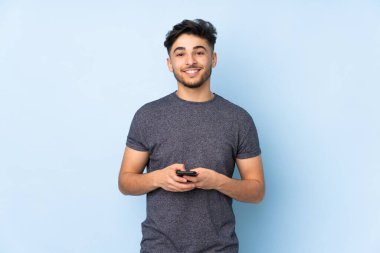 Arap yakışıklı adam izole edilmiş arka planda cep telefonuyla mesaj gönderiyor.