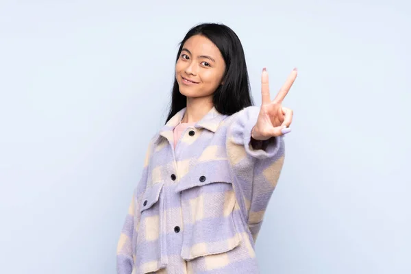 Έφηβη Κινέζα Απομονωμένη Μπλε Φόντο Χαμογελώντας Και Δείχνοντας Σύμβολο Της — Φωτογραφία Αρχείου