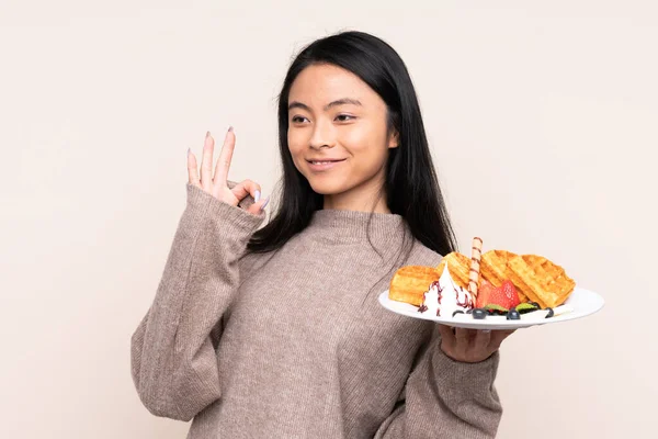 Tiener Aziatische Meisje Holding Wafels Geïsoleerd Beige Achtergrond Tonen Teken — Stockfoto