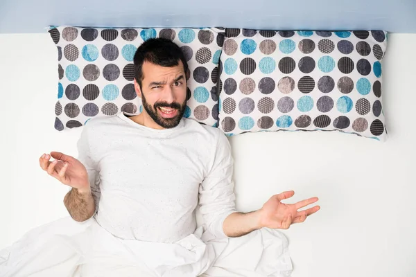 Man in bed in top view unhappy for not understand something