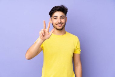 Soyutlanmış geçmişi olan yakışıklı Arap bir adam mutlu ve parmaklarıyla üçe kadar sayıyor.