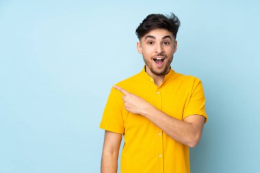 Tarafsız bir geçmişi olan yakışıklı bir Arap. Şaşırmış ve işaret ediyor.