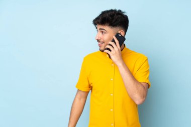 Arbiyalı yakışıklı adam izole edilmiş arka planda biriyle cep telefonuyla sohbet ediyor.