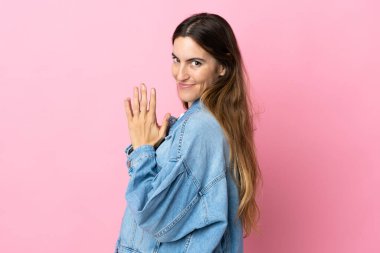 Pembe arka planda izole edilmiş genç beyaz kadın bir şeyler planlıyor.