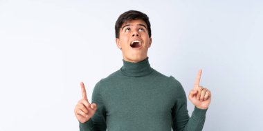 Izole mavi arka plan üzerinde Yakışıklı adam şaşırttı ve işaret