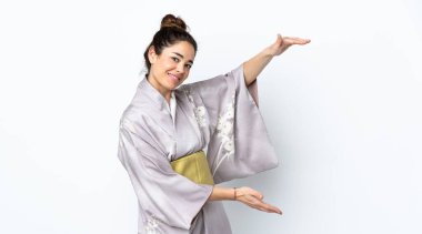 İzole edilmiş arka plan üzerinde kimono giyen bir kadın reklam koymak için kopyalama alanı tutuyor