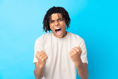 Genç Afro-Amerikalı adam, izole edilmiş mavi arka planda kötü bir durum yüzünden hayal kırıklığına uğradı.