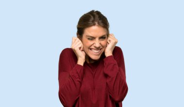 Sarışın kadın hayal kırıklığına uğramış ve elleri mavi arka planda olan kulakları kapatmış.