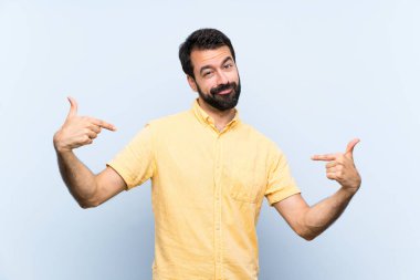 Sakallı genç adam soyutlanmış mavi arka planda gururlu ve kendini beğenmiş