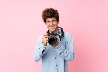 Uzman bir kamerayla izole edilmiş pembe arka planı olan genç beyaz bir adam.
