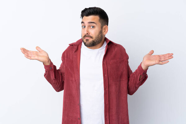 Young handsome man with beard wearing a corduroy jacket over isolated white background having doubts while raising hands