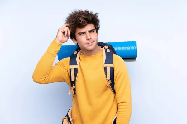 Joven Montañero Con Una Gran Mochila Sobre Fondo Azul Aislado — Foto de Stock