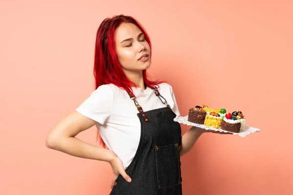 Konditor Hält Muffins Auf Rosa Hintergrund Und Leidet Unter Rückenschmerzen — Stockfoto