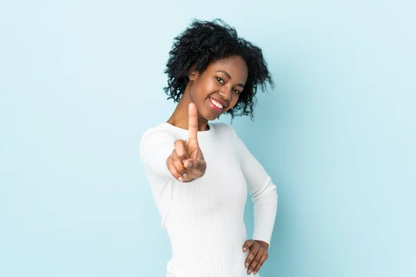 青の背景に孤立した若いアフリカ系アメリカ人女性が指を見せて持ち上げる — ストック写真