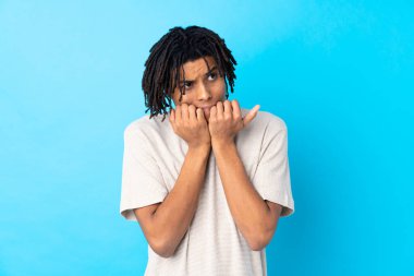 Genç Afro-Amerikalı bir adam izole edilmiş mavi arka planda gergin ve korkmuş bir şekilde elleriyle suni teneffüs yapıyor.