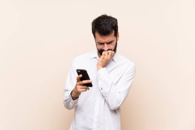 Elinde cep telefonu olan sakallı genç adamın şüpheleri var.