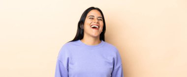 Genç Latin kadın arka planda yalnız gülüyor.