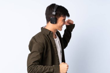 Yakışıklı adam soyutlanmış mavi arka planda müzik ve dans dinliyor.