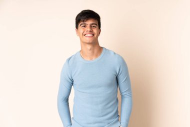 İzole edilmiş bej arka planda yakışıklı bir adam gülüyor.