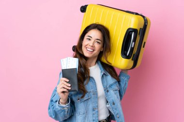 İzole edilmiş mavi arka planda, bavullu ve pasaportlu bir kadın.