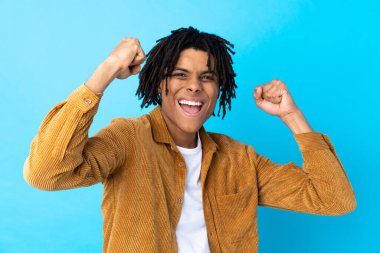 Mavi arka planda kadife ceketli genç Afrikalı Amerikalı bir adam zaferi kutluyor.