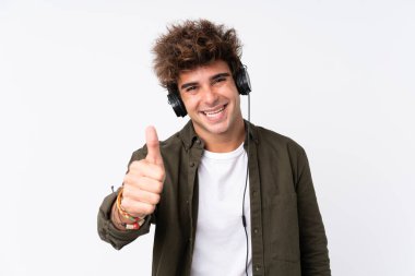 Genç yakışıklı adam izole beyaz duvarın ardından müzik dinliyor.