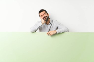 Sakallı, elinde kocaman boş bir levha olan yakışıklı genç adam,... hareketsiz bir uyku hareketi yapıyor.