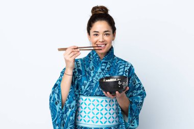 İzole edilmiş beyaz arka planda kimono giyen bir kadın elinde çubuklu erişte kasesi tutuyor.