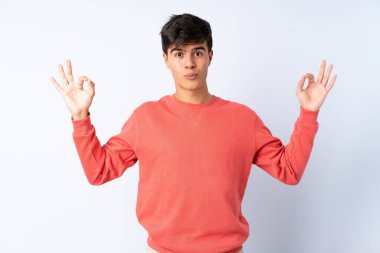 Zen pozunda, izole edilmiş mavi arka planda yakışıklı bir adam.