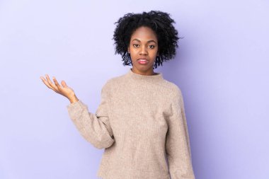 Genç Afrikalı Amerikalı kadın, mor arka planda izole edilmiş, şüpheli hareketler yapıyor.