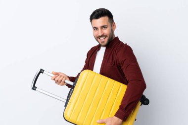 Genç yakışıklı adam izole edilmiş beyaz arka planda seyahat valiziyle tatilde.