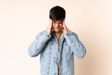 Tecrit edilmiş bej arkaplan ve baş ağrısı olan yakışıklı bir adam.