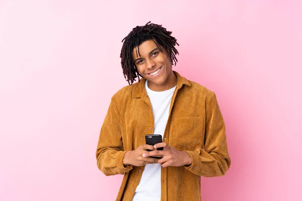 身穿灯芯绒夹克 背景为粉色的年轻非洲裔美国人用手机传达了一个信息 — 图库照片