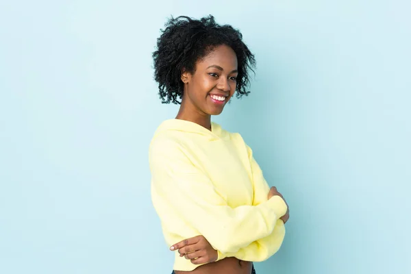 Ung Afroamerikansk Kvinna Isolerad Blå Bakgrund Tittar Sidan Och Ler — Stockfoto