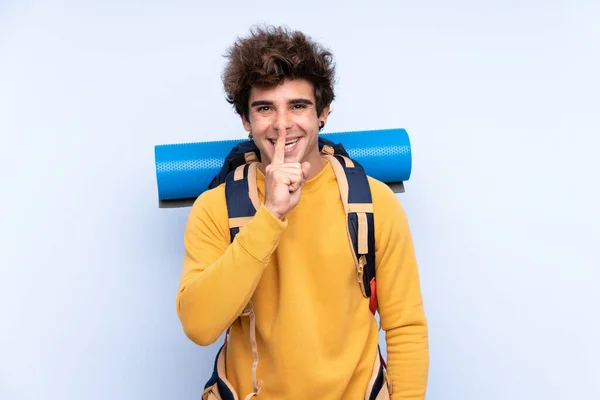 Joven Montañero Con Una Gran Mochila Sobre Fondo Azul Aislado — Foto de Stock