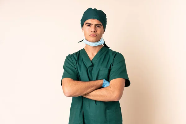 身穿蓝色制服的外科医生在孤立的背景下交叉着双臂 — 图库照片