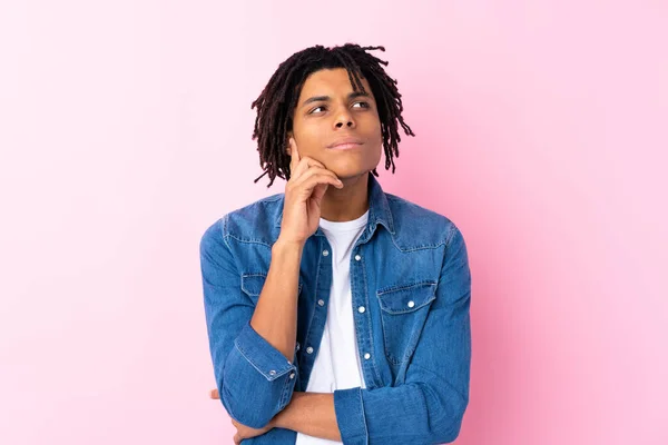 Young African American man with jean shirt over isolated pink background thinking an idea