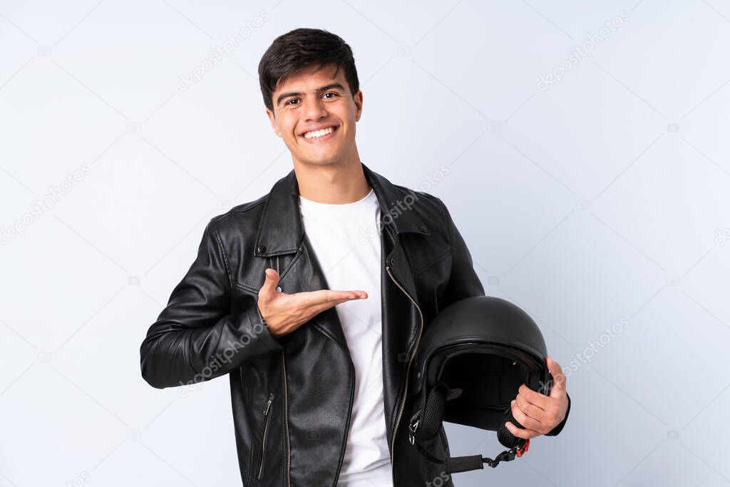 Man with a motorcycle helmet over isolated blue background extending hands to the side for inviting to come
