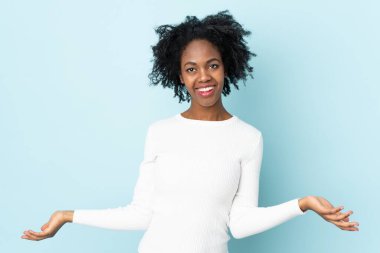 Genç Afrikalı Amerikalı kadın, mavi arka planda izole edilmiş. Şüpheleri var.