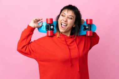 Genç Uruguaylı kadın pembe arka planda paten kayıyor ve yukarı bakıyor.