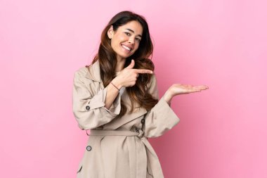 Arka planda izole edilmiş bir kadın. İlan vermek için avucunun içinde hayali bir alan tutuyor.