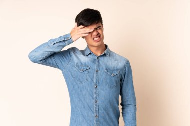 İzole edilmiş bej arkaplanı olan yakışıklı adam yorgun ve hasta bir yüz ifadesi var.