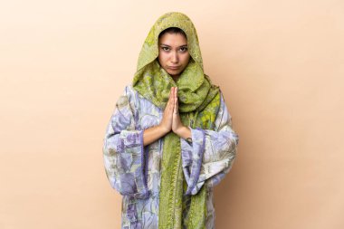 Bej arka planda izole edilmiş Hintli kadın avuç içlerini bir arada tutuyor. İnsan bir şey ister.