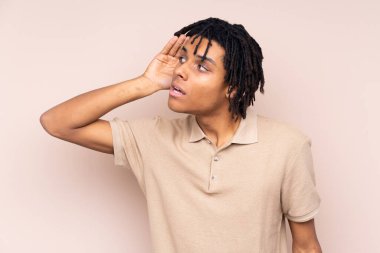 Genç Afrikalı Amerikalı bir adam izole edilmiş arka planda bir şeyler dinliyor.