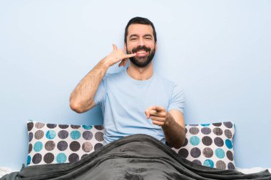 Yatakta telefon eden ve ön tarafı gösteren bir adam var.