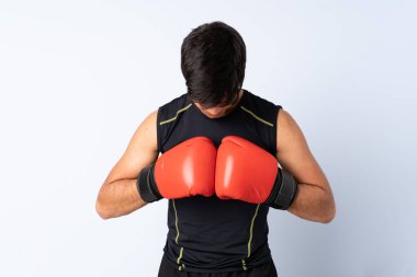 İzole edilmiş mavi arka planda boks eldivenli bir sporcu.